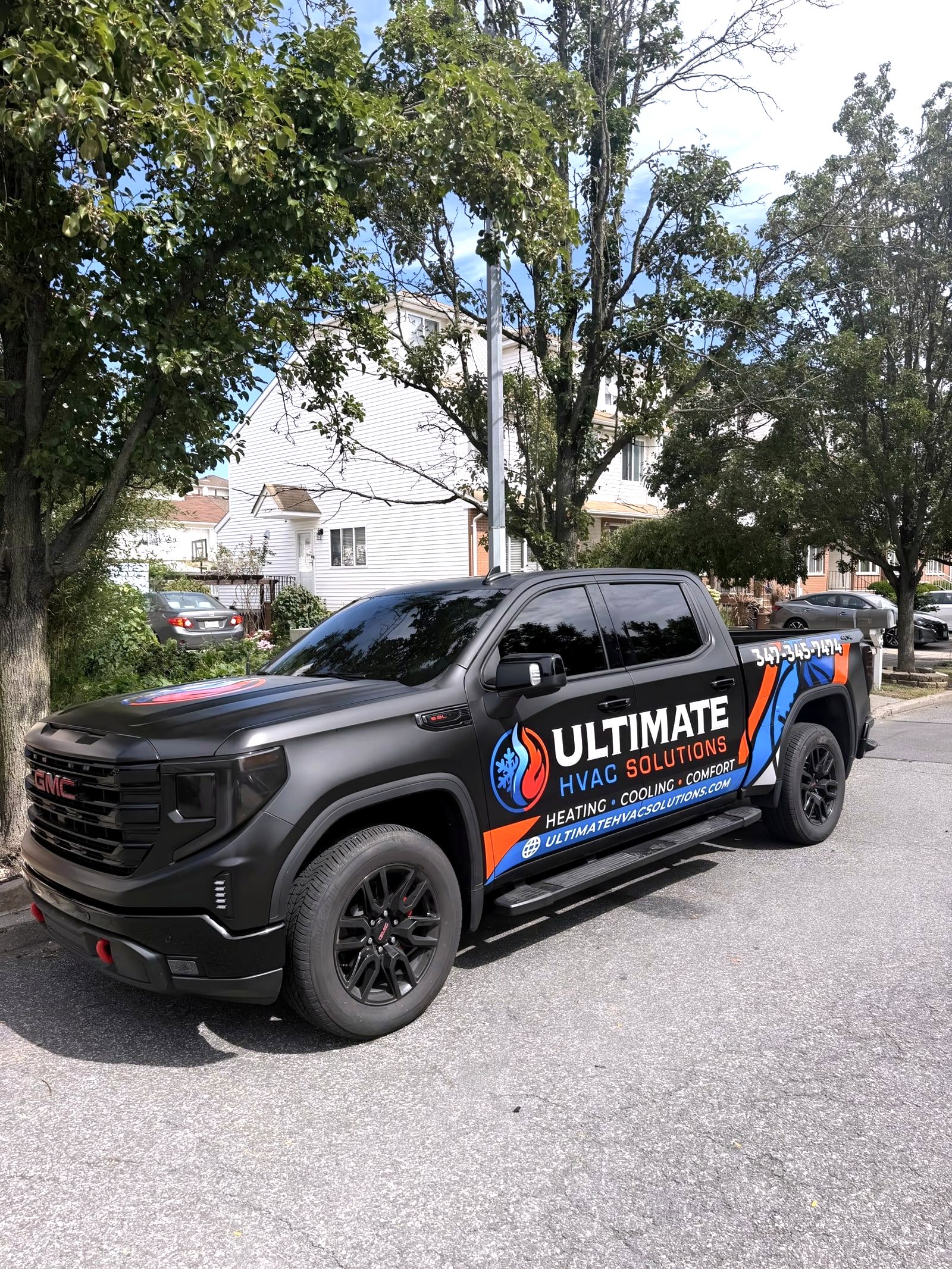 Black GMC pickup with Ultimate HVAC Solutions wrap parked on street